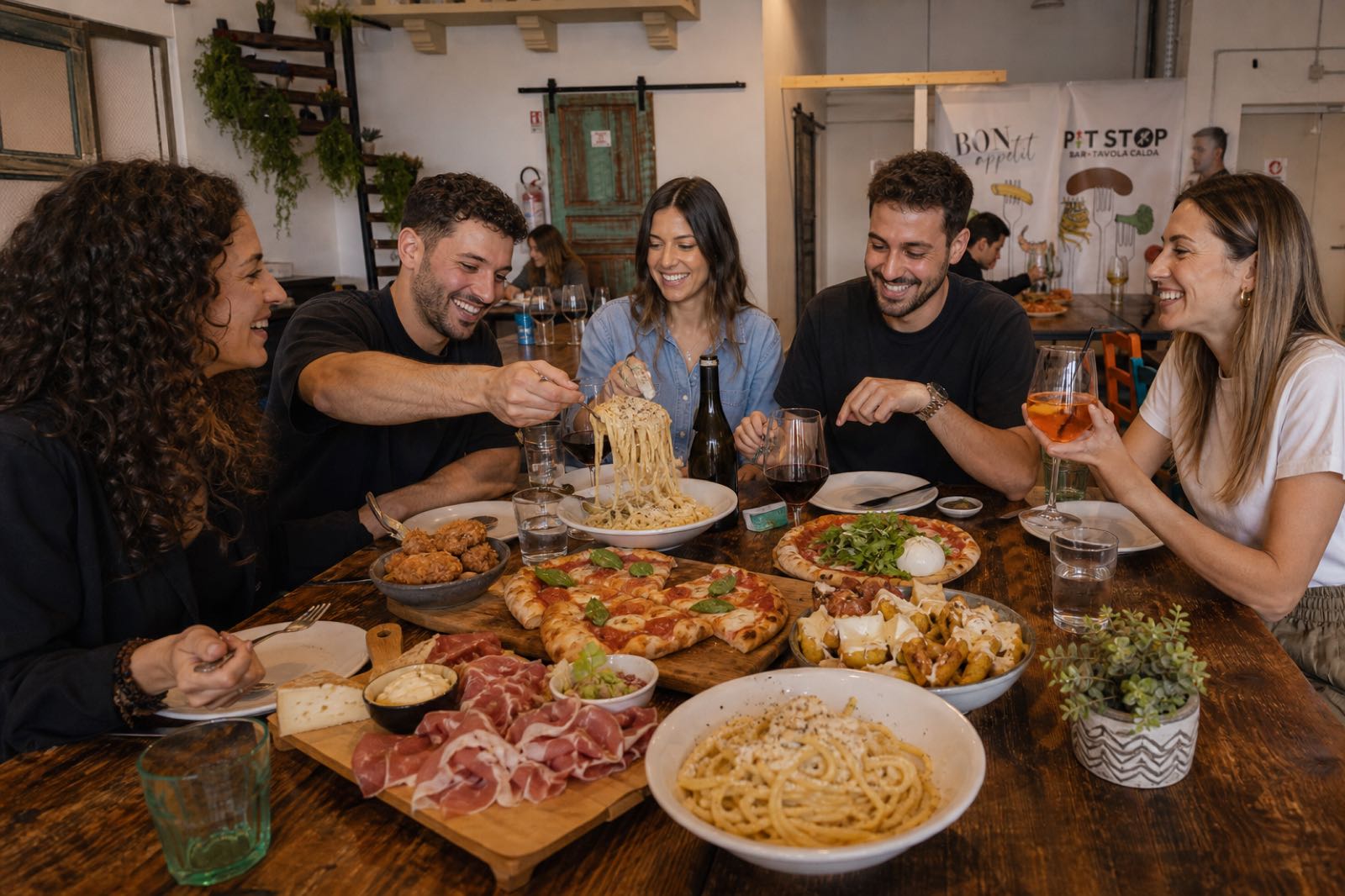 Amici a tavola con pizza, pasta e tagliere da PitStop